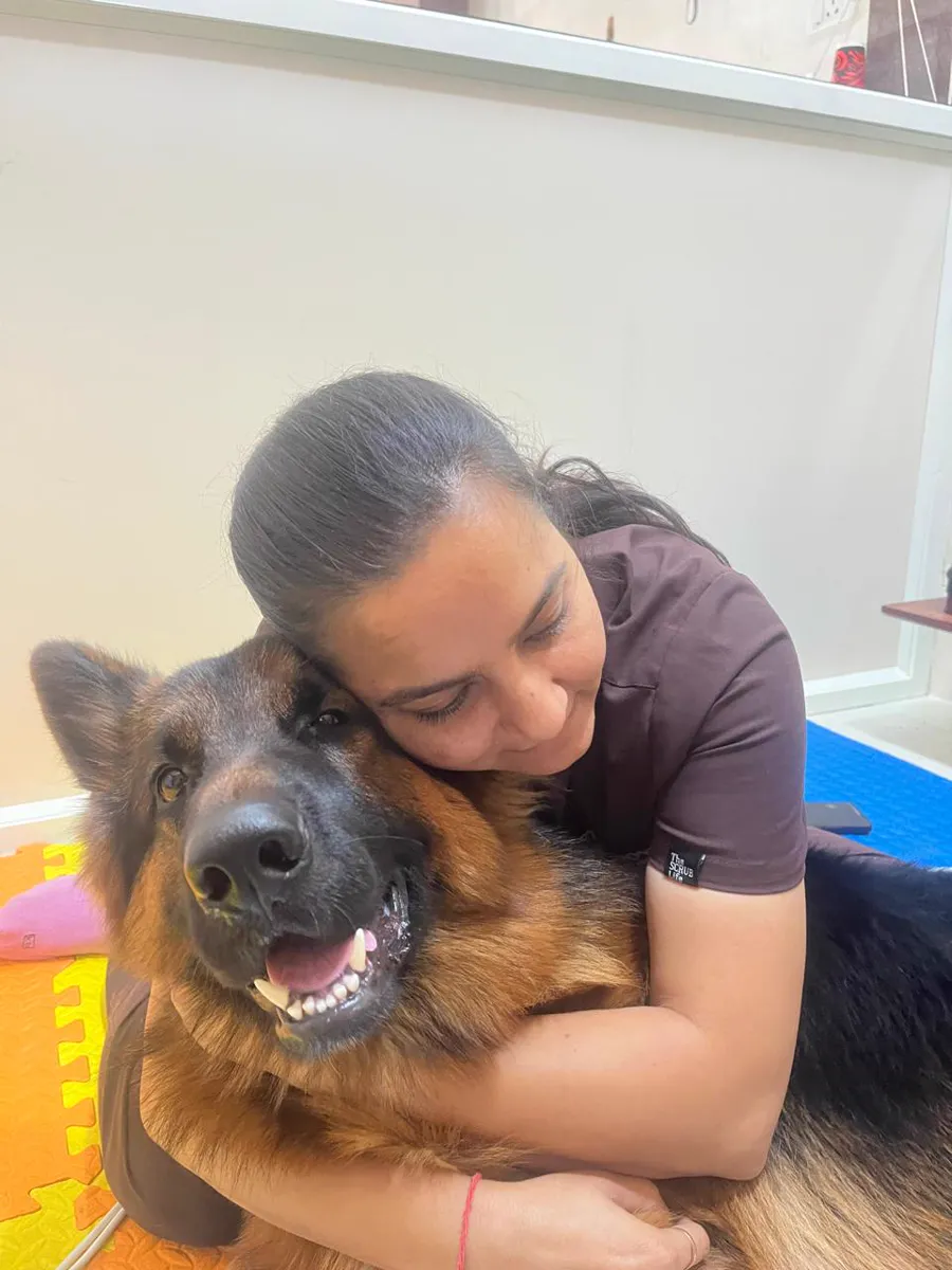 Dr. Dhanvi Patel holding a German Shepherd on the padded therapy mats at the Shilaj clinic