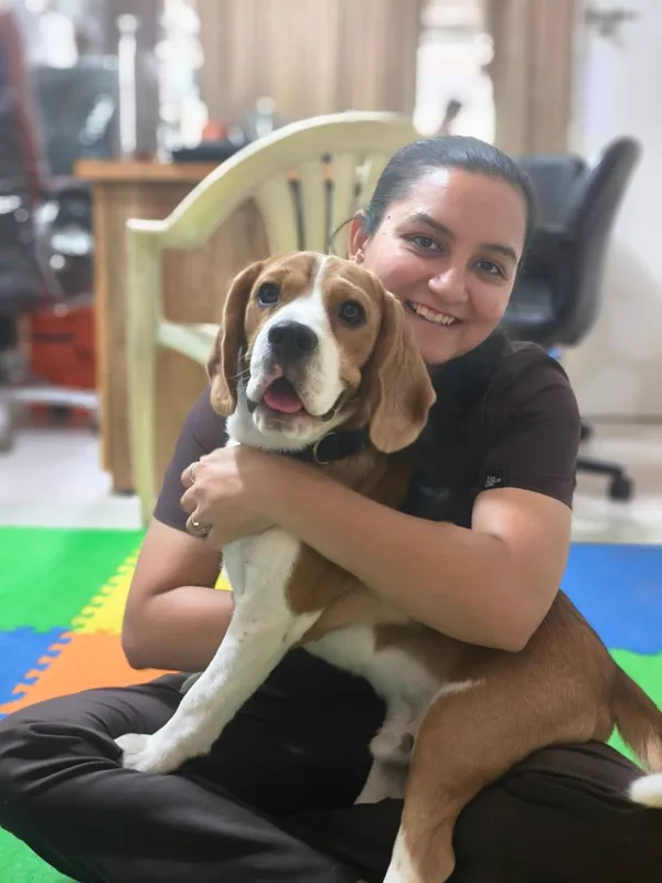 Dr. Dhanvi Patel sitting on the therapy mats at the clinic, holding a beagle