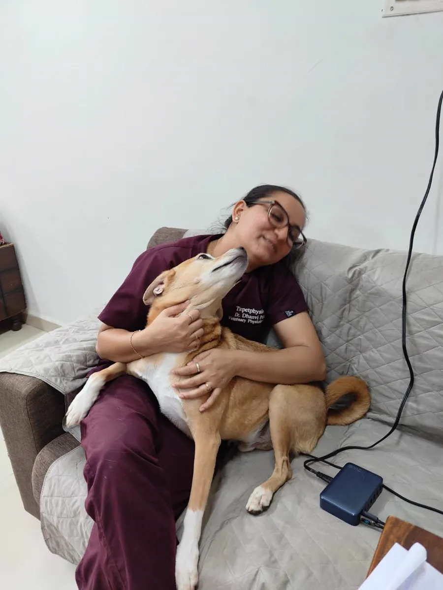 An Indian pariah dog resting against Dr. Dhanvi Patel during a home visit