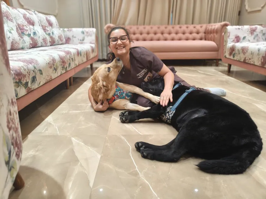 Dr. Dhanvi Patel sitting on the floor with two Labradors during a home visit